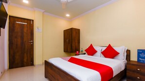 Ein Hotelzimmer mit einem hölzernen Bett, einem Nachttisch, einem Kleiderschrank und einem Deckenventilator.