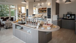Un bar à petit-déjeuner moderne proposant une grande variété d’aliments et de boissons, notamment des fruits, des viennoiseries et des machines à café.