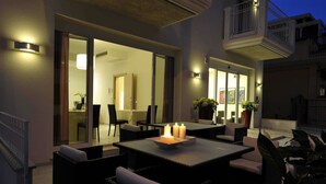 An outdoor dining area with tables and chairs, a balcony, and a view of the interior. - Residence Hotel Rubino (Riccione)