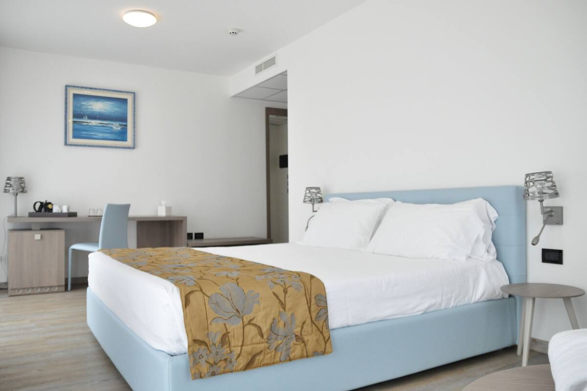 A modern hotel room with a bed, desk, and chair.