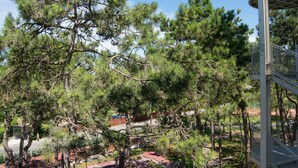 A multi-level outdoor area with trees, a spiral staircase, and a red pathway. - Fantinello Hotel (Caorle)