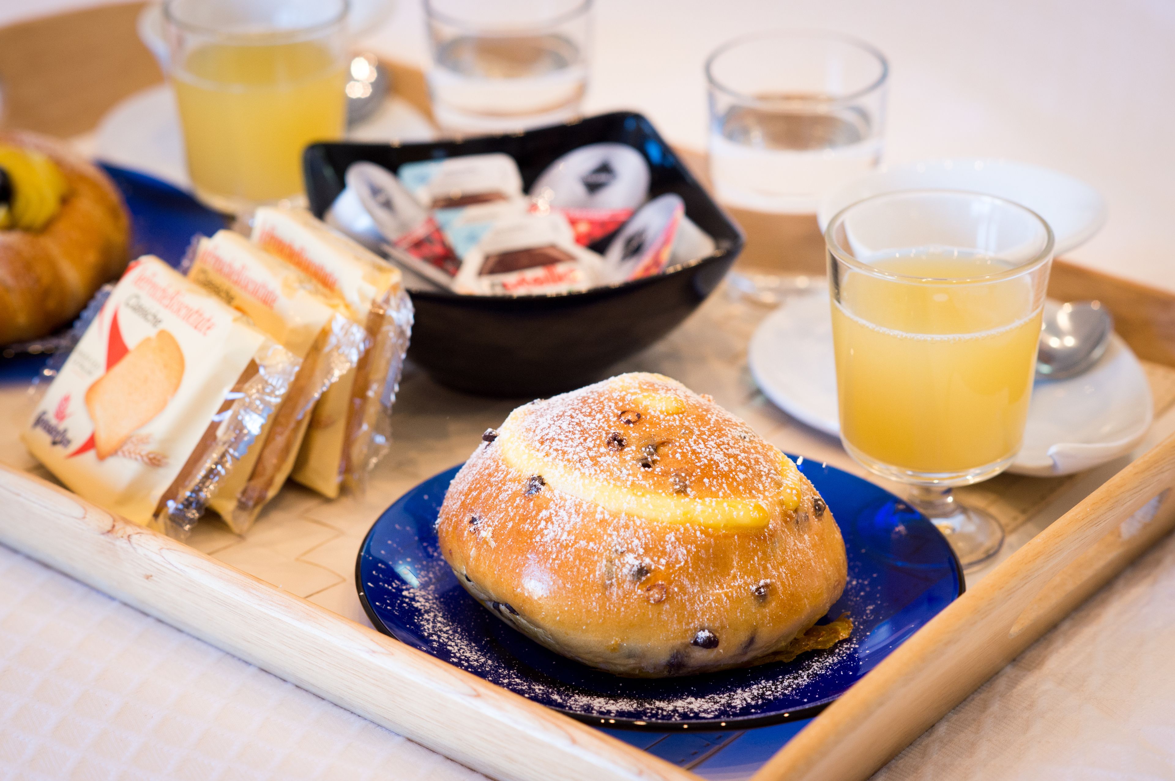 A tray with pastries, a bowl of donuts, and glasses of orange juice.