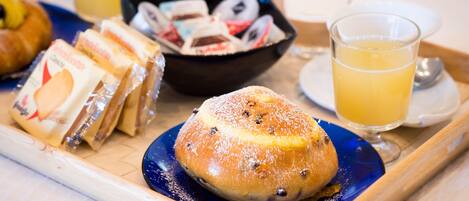 A tray with pastries, a bowl of donuts, and glasses of orange juice.