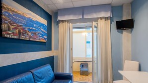 A modern room with a blue sofa, a white table, and a painting of a coastal town. - Casa Matilde (Sorrento)