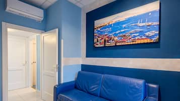 Habitación, varias camas | Área de sala de estar | Televisión de pantalla plana de 23 pulgadas con canales por cable