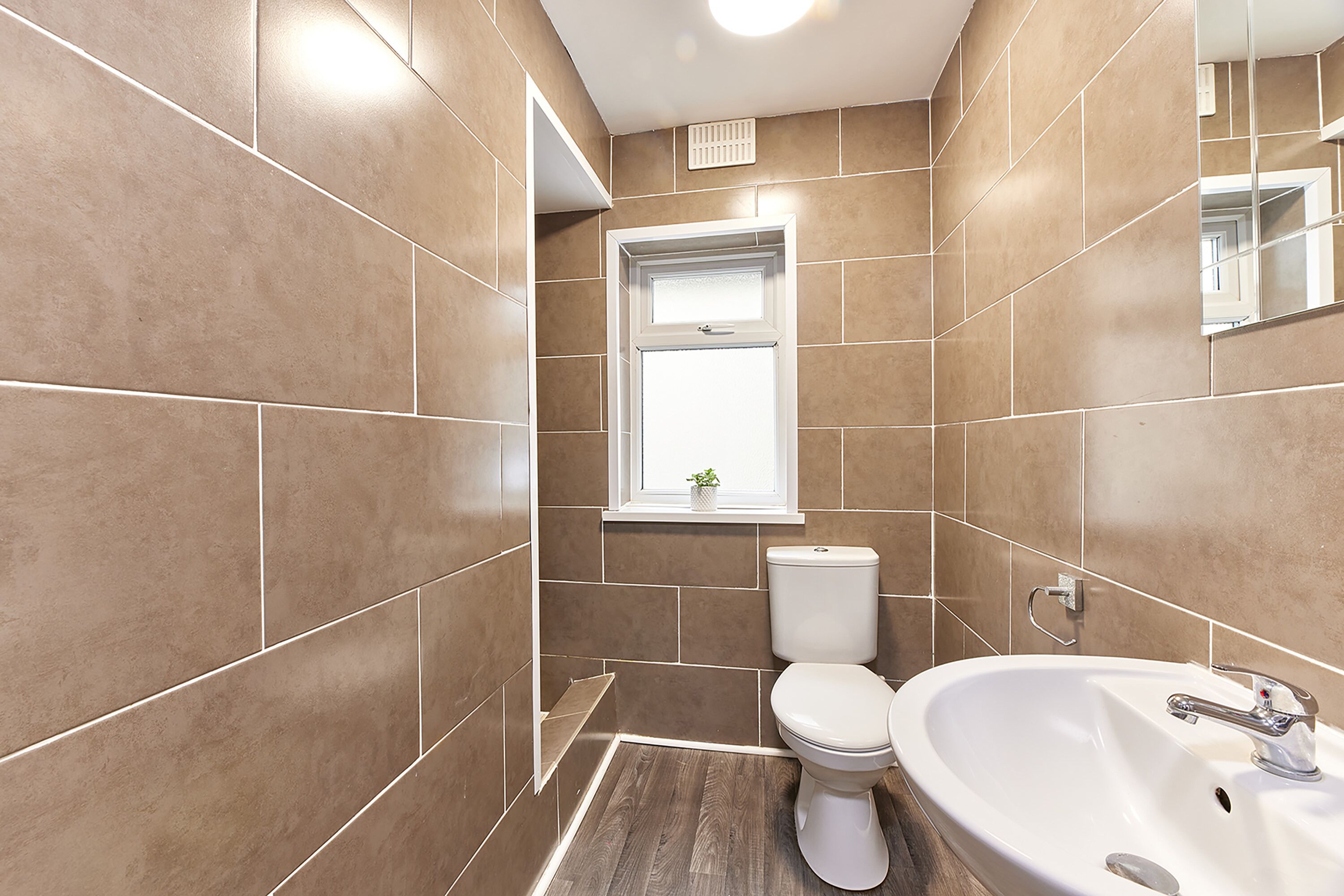 A modern bathroom with a toilet, sink, and window.