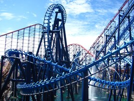 A roller coaster with a steep drop and a loop, surrounded by a steel framework.