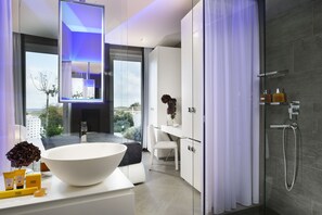 Ein modernes Badezimmer mit einem großen weißen Waschbecken, einer Dusche und Blick ins Freie.