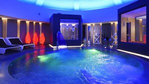 A modern indoor pool area with a circular design, multiple lounge chairs, and a central water feature. - Soleinme Resort (Ostuni)