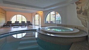 A spa area with a hot tub, lounge chairs, and large arched windows.