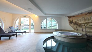 A spa area with a hot tub, lounge chairs, and large arched windows.