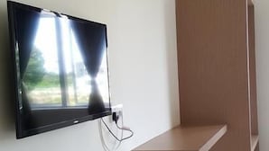 Een moderne kamer met een flatscreen televisie aan de muur, een houten bankje en een betegelde vloer.