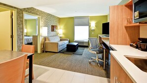 A hotel room with a sofa, a dining table with chairs, a TV, and a kitchenette. - Home2 Suites by Hilton Smyrna Nashville (Smyrna)