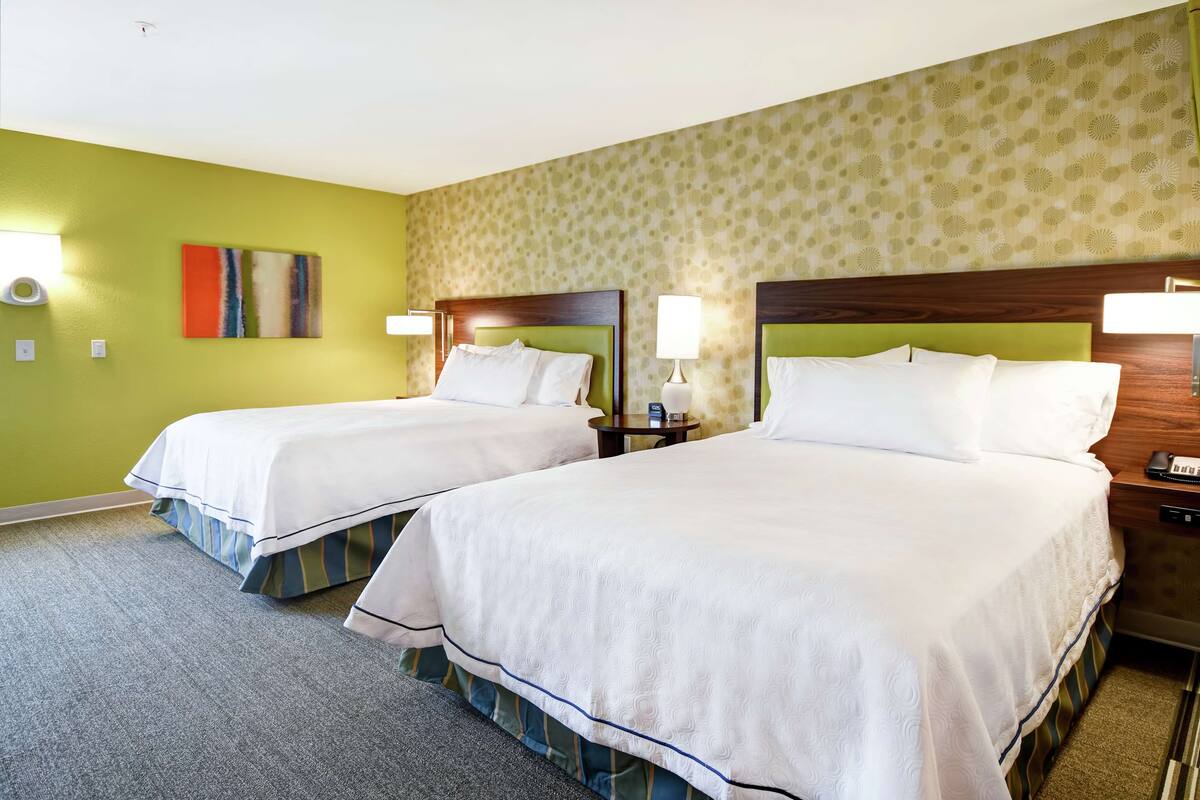 A hotel room with two beds, green walls, and a patterned wallpaper.