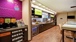 A coffee shop with a counter, coffee machines, and a display of mugs. - Home2 Suites by Hilton Smyrna Nashville (Smyrna)