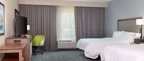 A hotel room with two beds, a desk, a chair, a television, and a window with curtains.