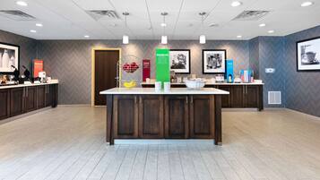 A modern reception area with a central counter, wooden cabinets, and a herringbone-patterned wall.