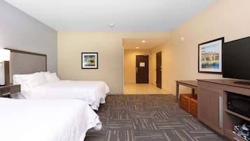 A hotel room with two beds, a television, a desk, and a door leading to another room.