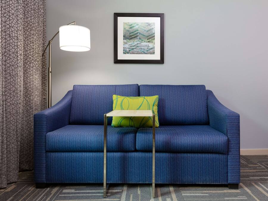Un canapé bleu avec un coussin vert et une petite table placée devant.