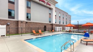 Un Hampton Inn con zona de piscina, sillones de descanso y sombrillas.