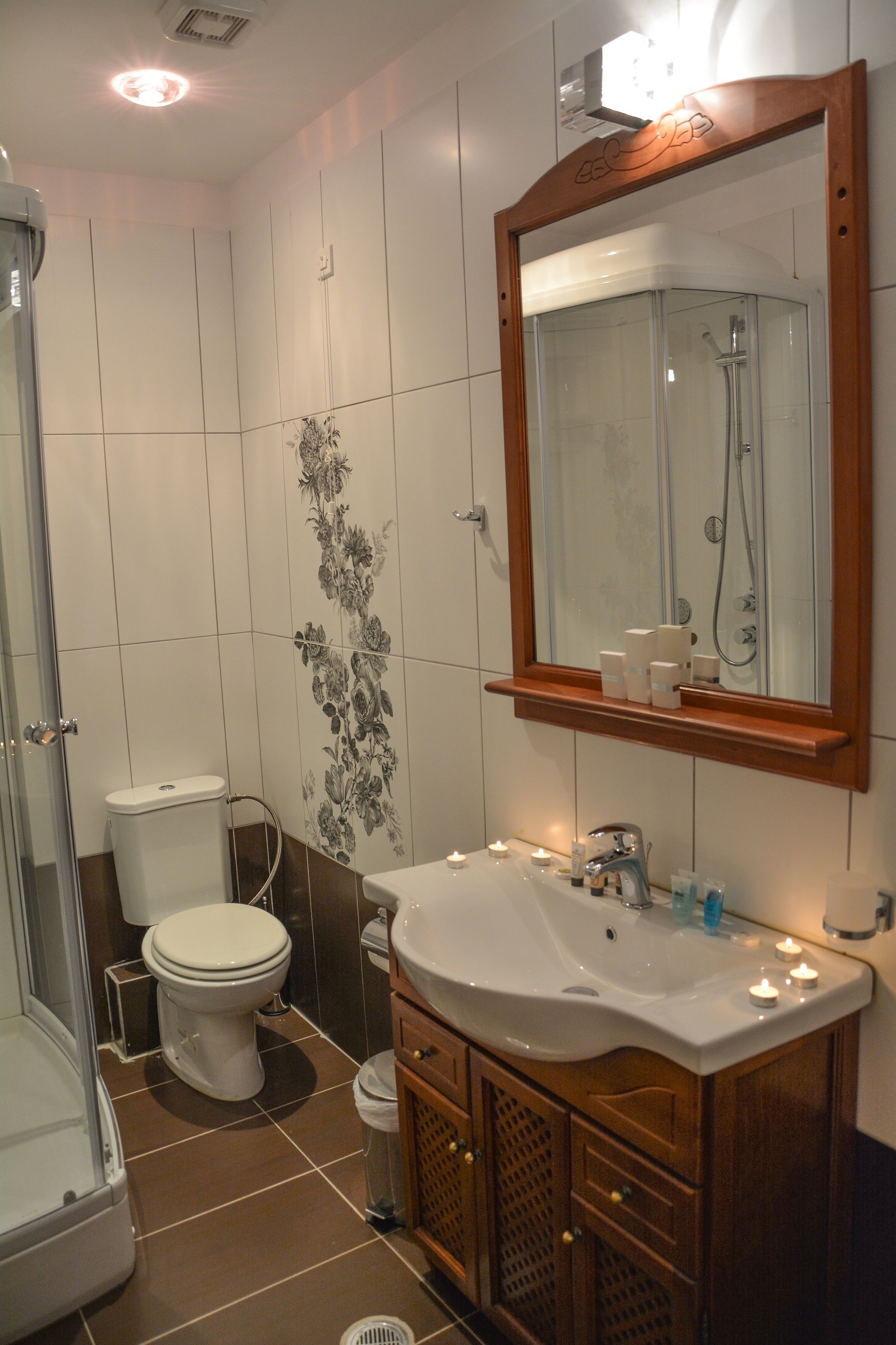 A bathroom with a toilet, sink, mirror, and shower.