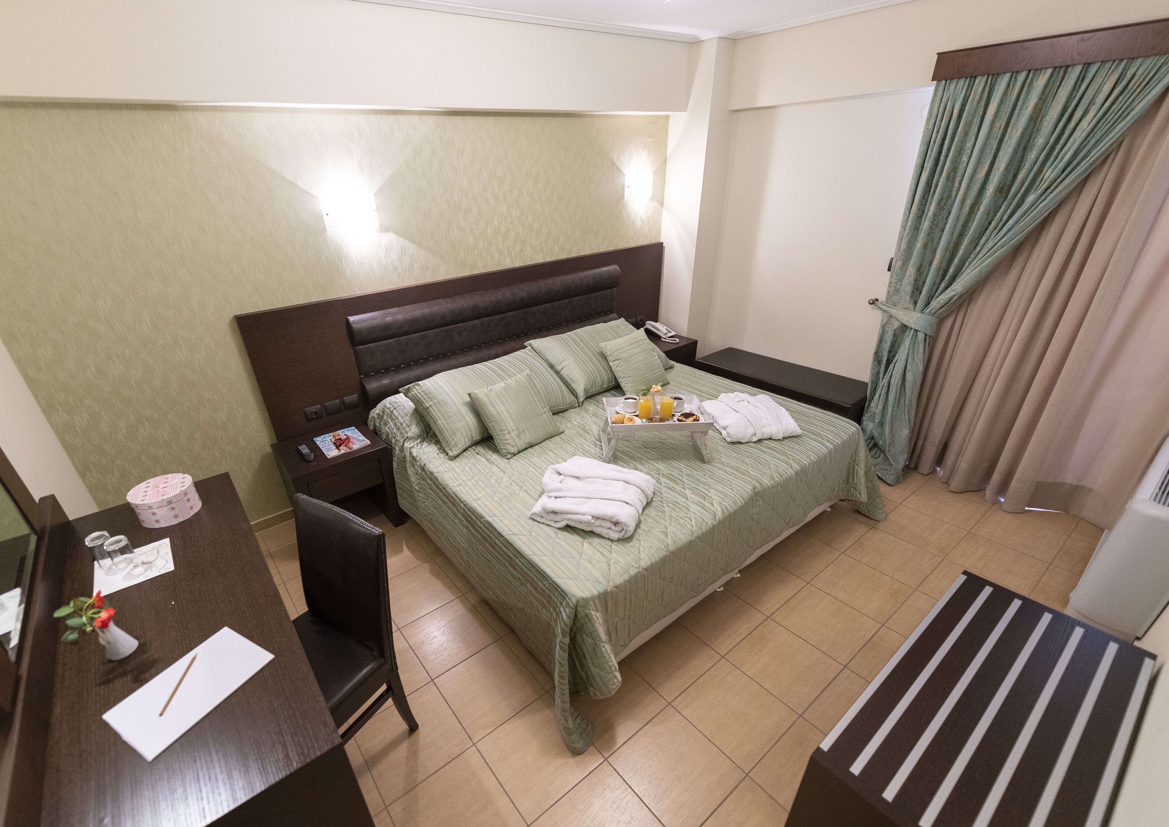 Una habitación de hotel con cama, mesita de noche, silla y un escritorio pequeño.