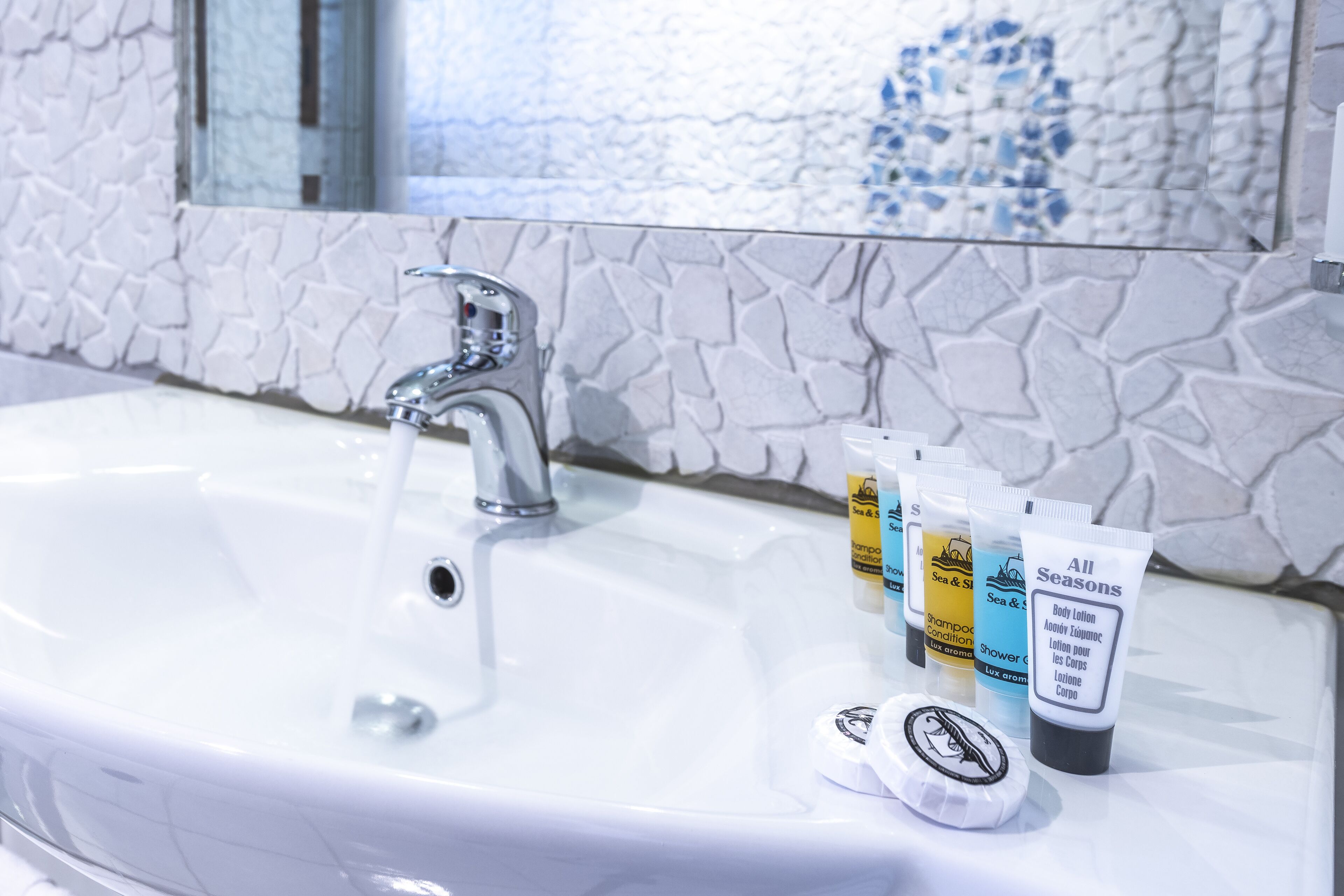 A bathroom sink with a mirror above it, a faucet, and three toiletries on the sink.