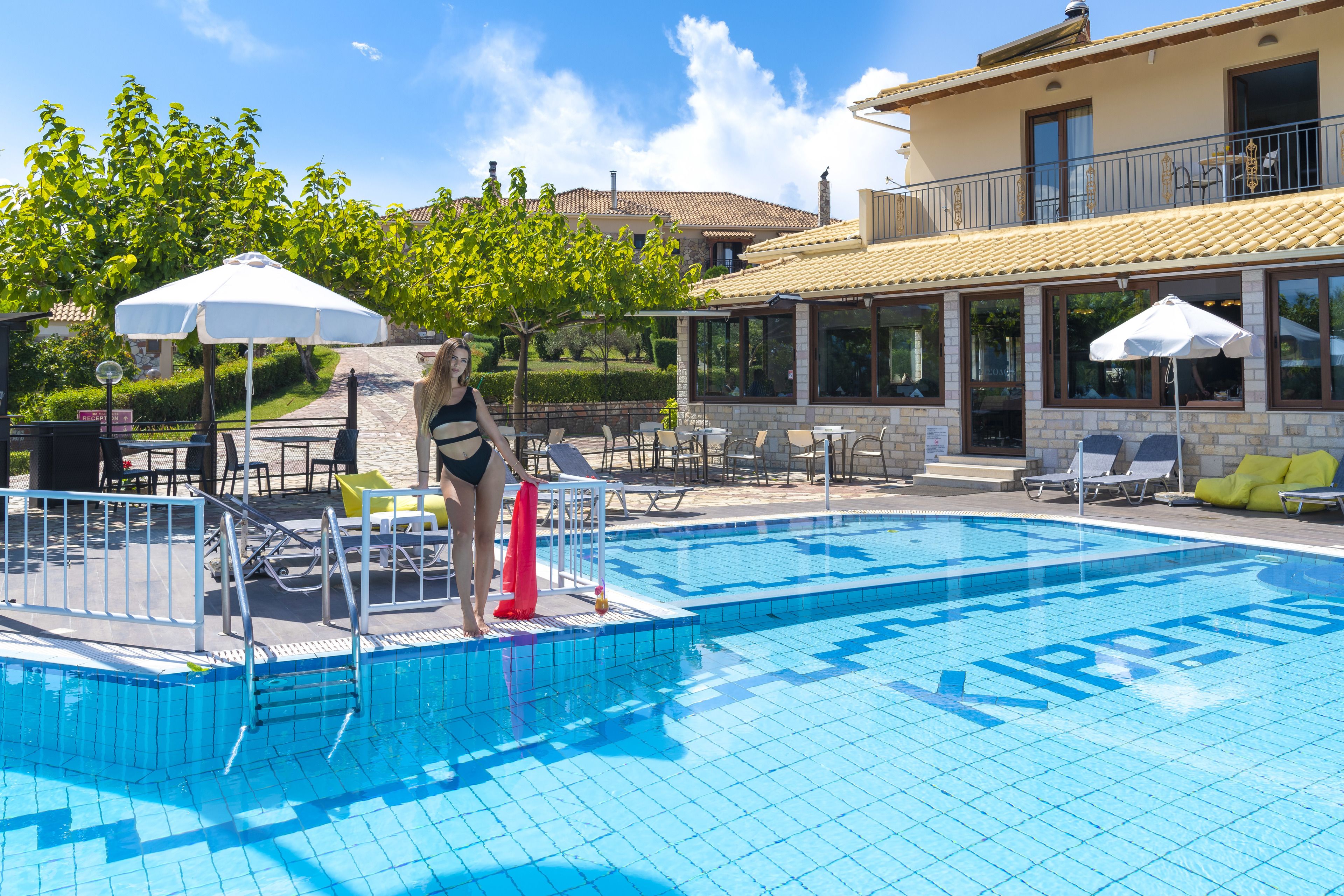 Une piscine avec une terrasse carrelée, des chaises longues et des parasols.