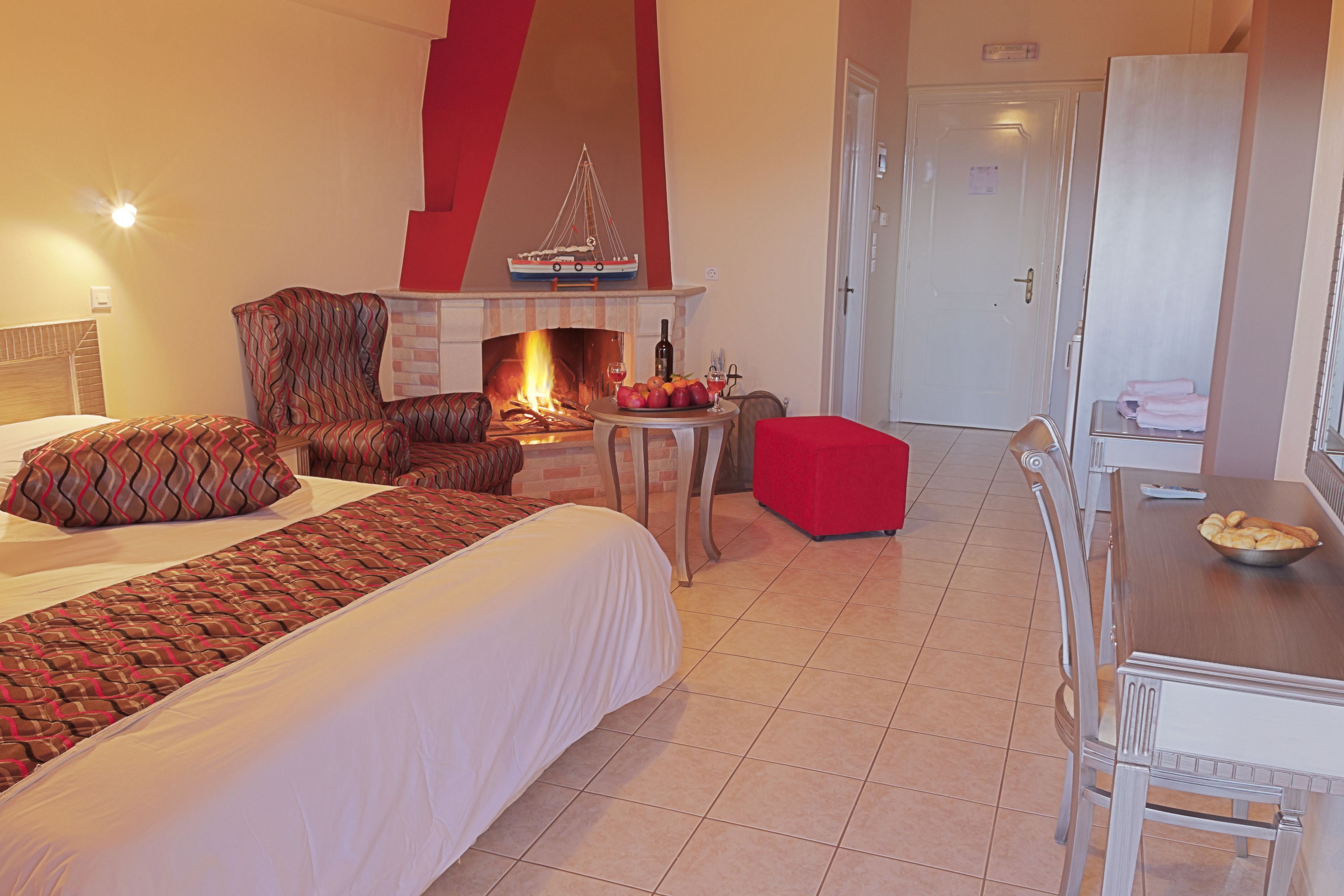 Una habitación de hotel con una cama, chimenea, mesa de comedor con sillas y un armario.