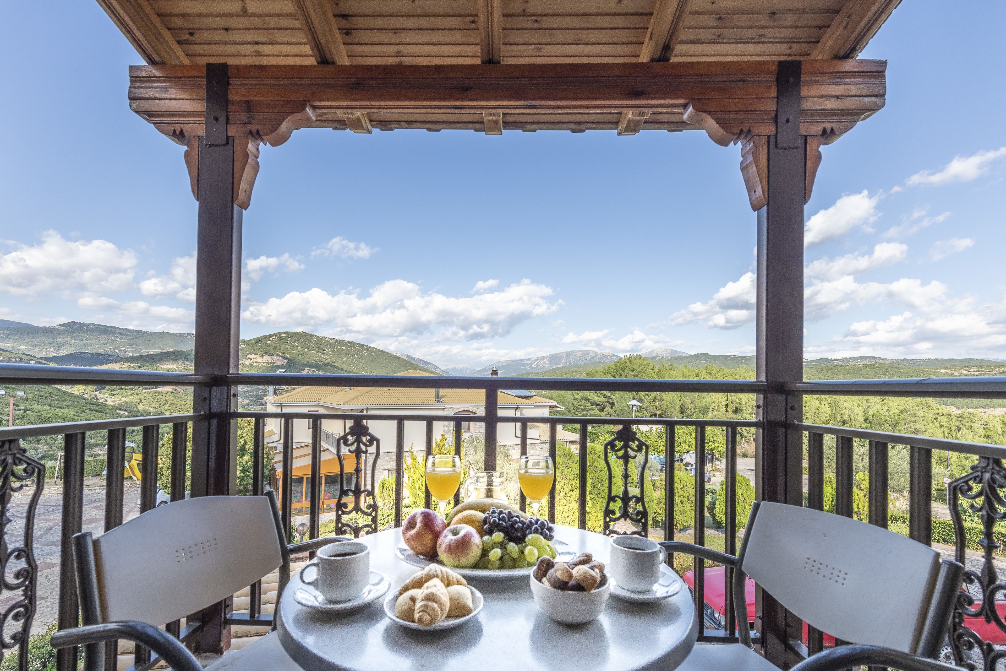 A balcony with a table set for breakfast, overlooking a mountainous landscape.