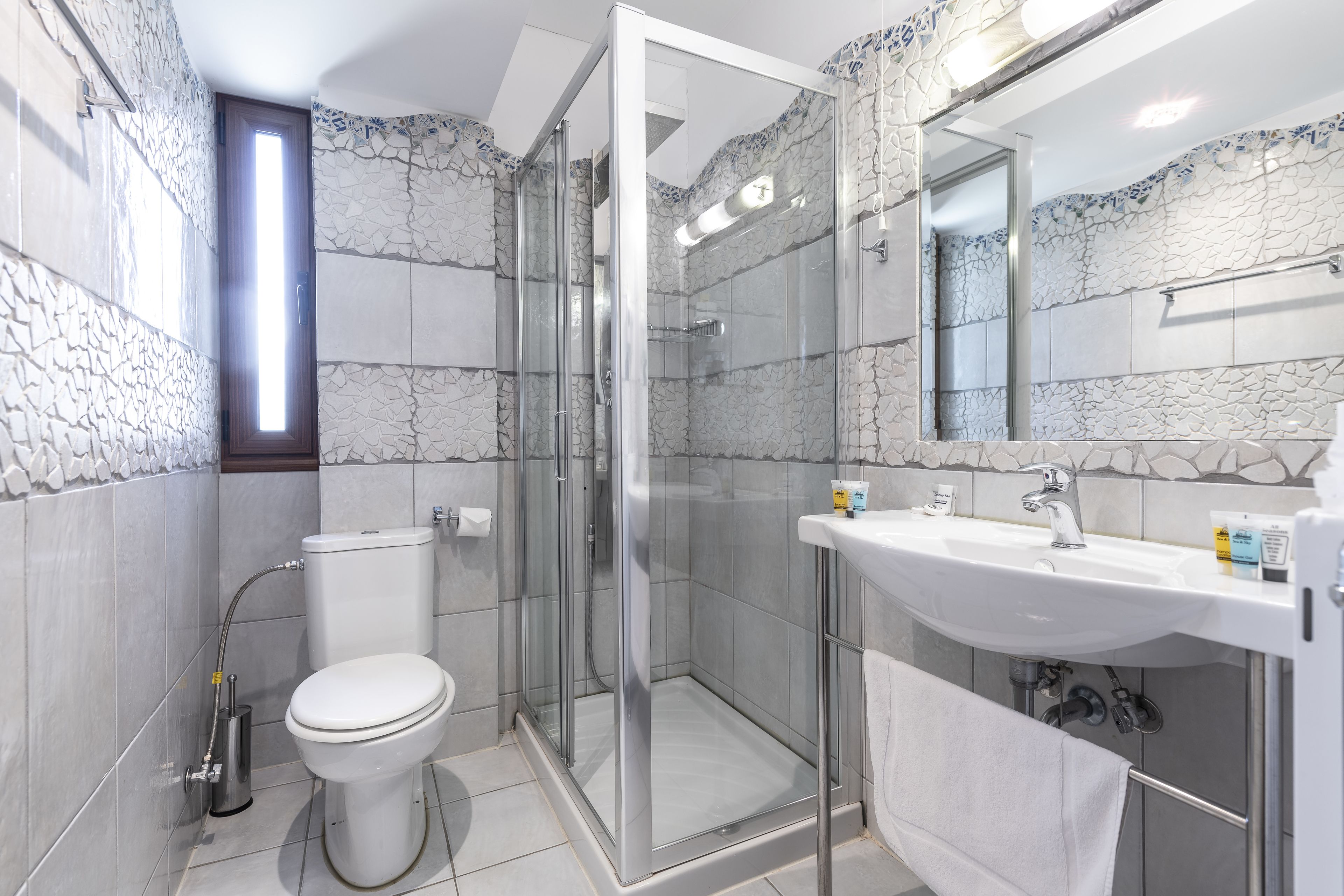 A modern bathroom with a glass shower enclosure, a white sink, and a toilet.