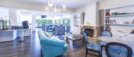 Amplia sala de estar con sofá azul, mesa de comedor y sillas, chimenea y estantería.
