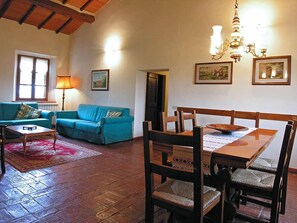 A cozy living room with a wooden dining table, blue sofa, and a chandelier. - Poggio del Sole (Castiglione del Lago)