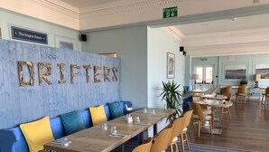 Un restaurante con pared azul, mesas de madera y asientos acolchados en azul y amarillo.