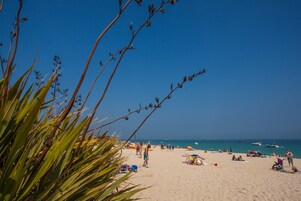 Una playa con gente, sombrillas y barcos.