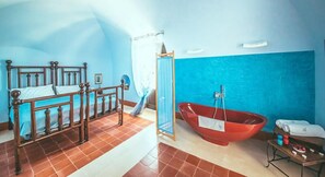 Ein Schlafzimmer mit einem hölzernen Bett, einer roten Badewanne und einem kleinen Tisch mit Pflegeprodukten.
