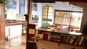 Una sala de estar moderna con un sofá de cuero, una mesa de centro con libros, una estantería y una cocina al fondo.