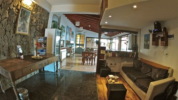 Amplia sala de estar con pared de piedra, muebles de madera y una cocina al fondo.