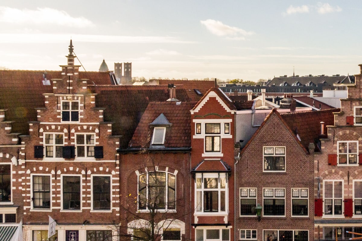 Uma fileira de edifícios em estilo europeu tradicional, com características arquitetônicas marcantes, incluindo telhados pontudos e fachadas de tijolo.