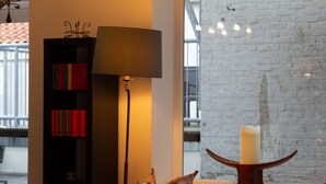Ein modernes Zimmer mit Bücherregal, Stehlampe, Bett und großem Fenster mit Blick ins Freie.