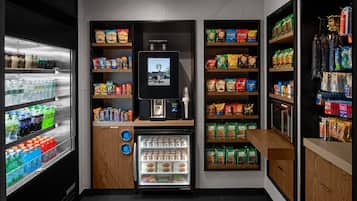 Un quiosco autoservicio con un refrigerador de bebidas, estantes para snacks y una máquina de café.
