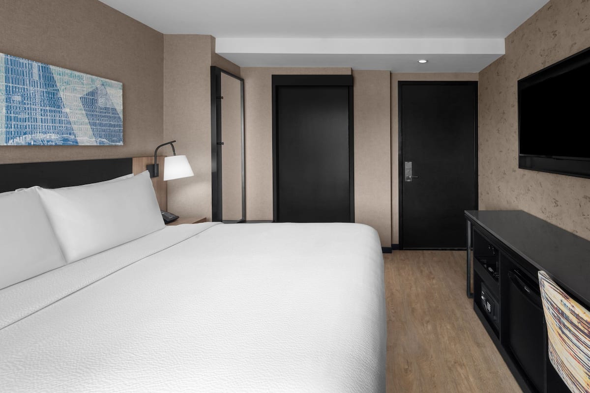Ein Hotelzimmer mit einem großen Bett, einem Schreibtisch, einem Fernseher und einer Tür.