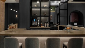 A modern kitchen with a central island, bar seating, and a coffee machine.