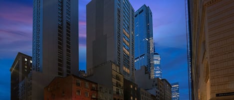 Un paisaje urbano con edificios altos, incluyendo un rascacielos destacado con ventanas de vidrio reflectante.