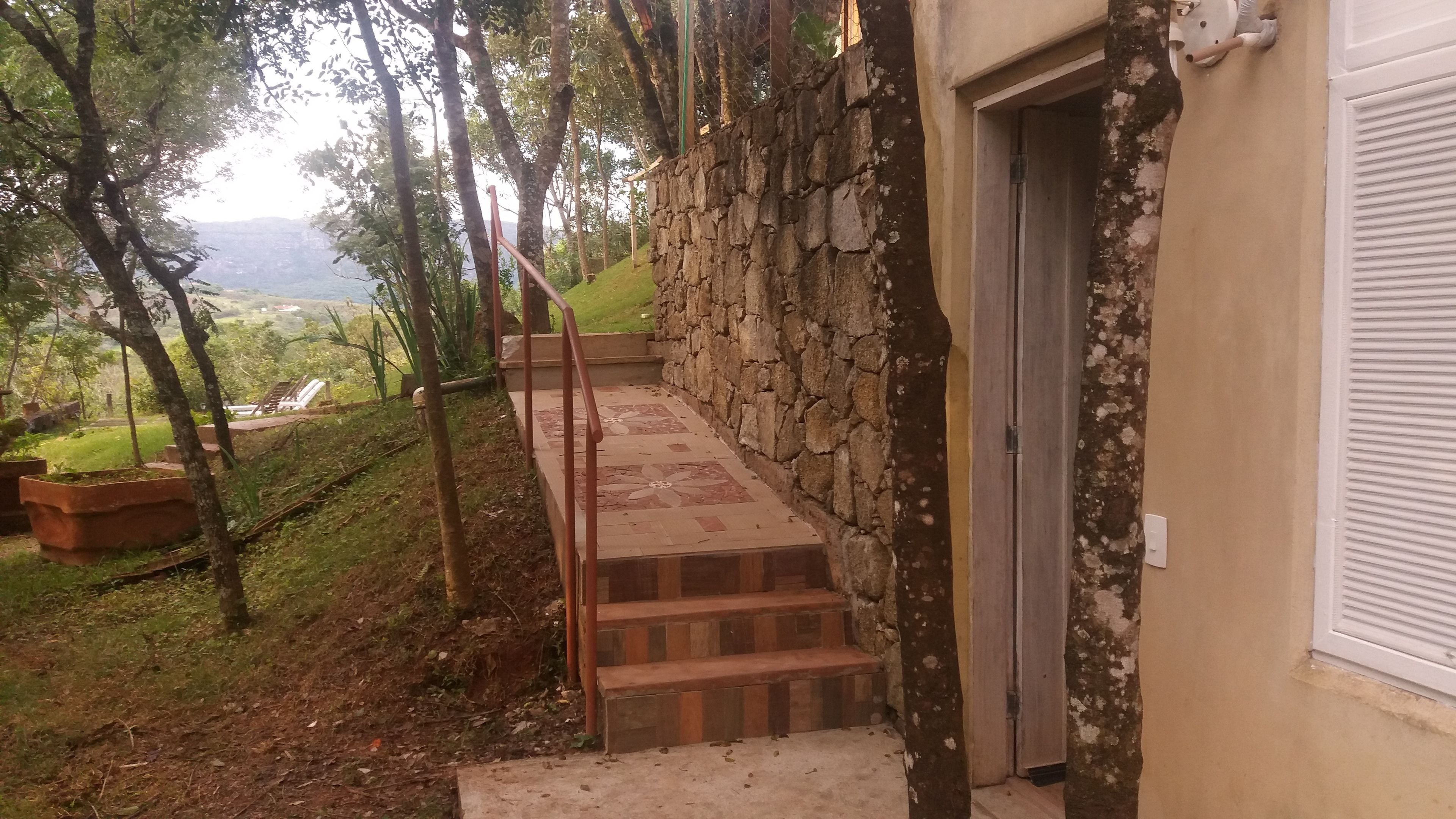Una escalera de piedra que lleva a una puerta, rodeada de vegetación y con vistas al paisaje.