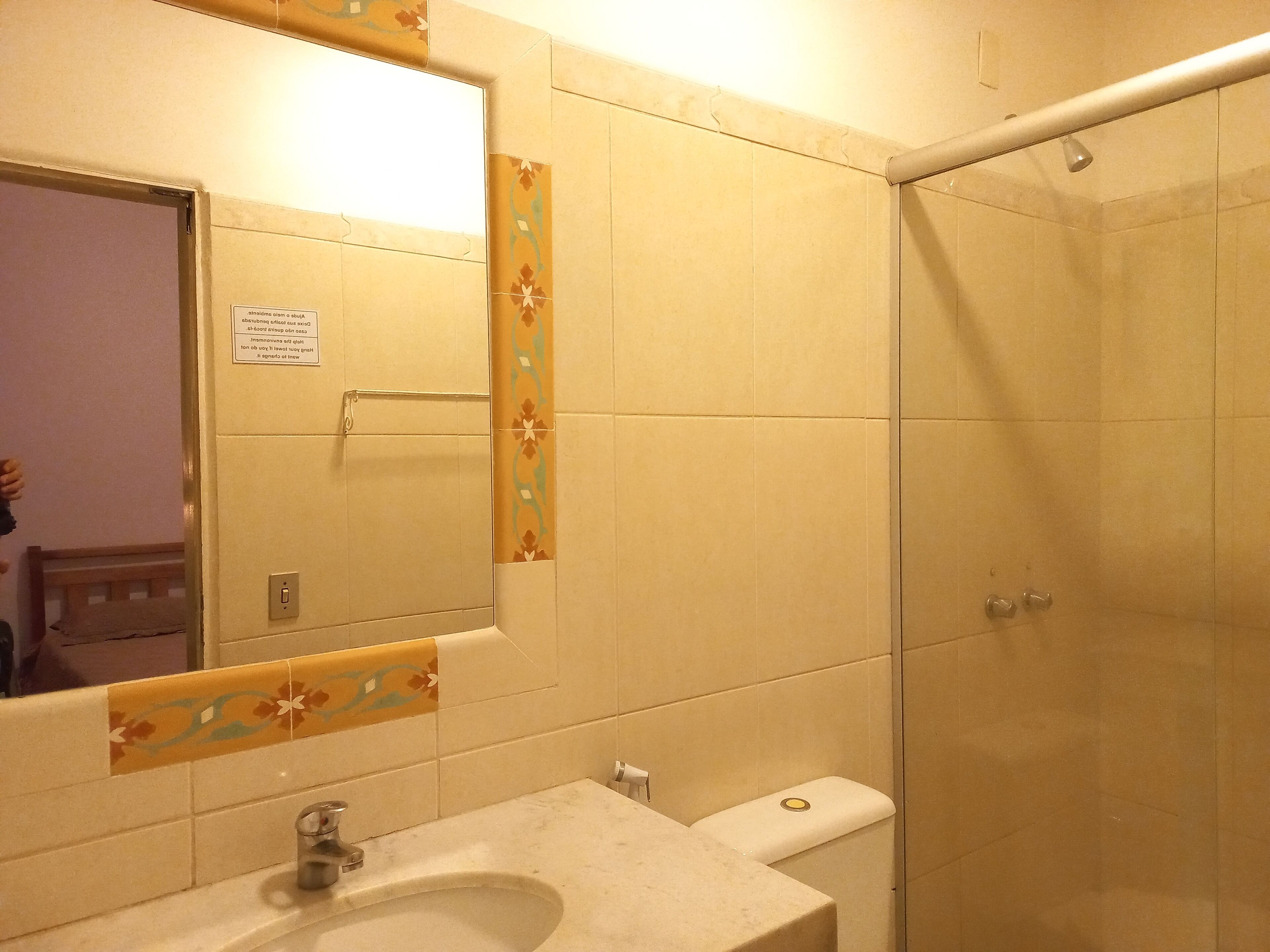 Un baño con lavamanos, espejo, inodoro y ducha.
