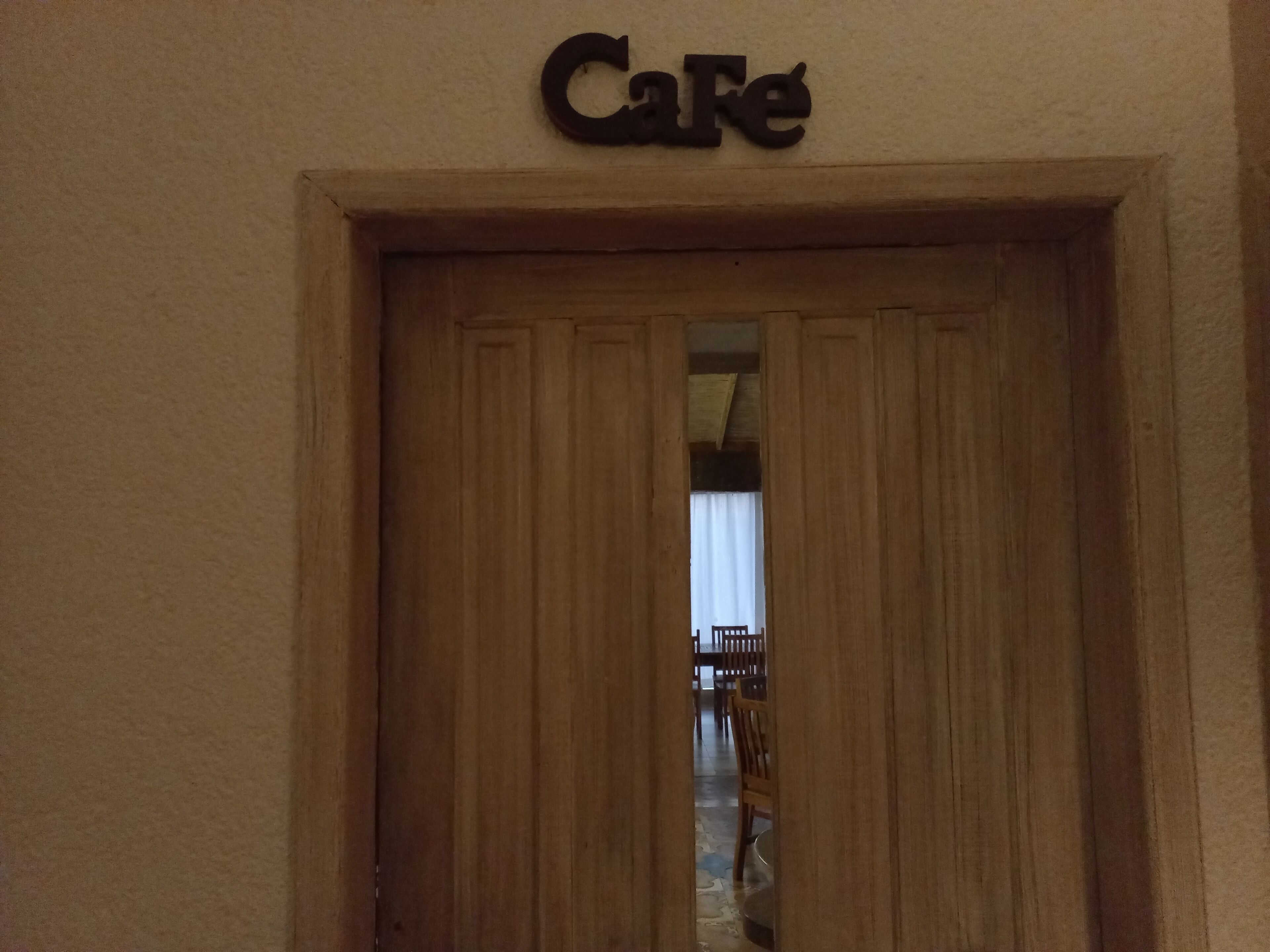 Una puerta de madera con un letrero encima que dice "Cafe".