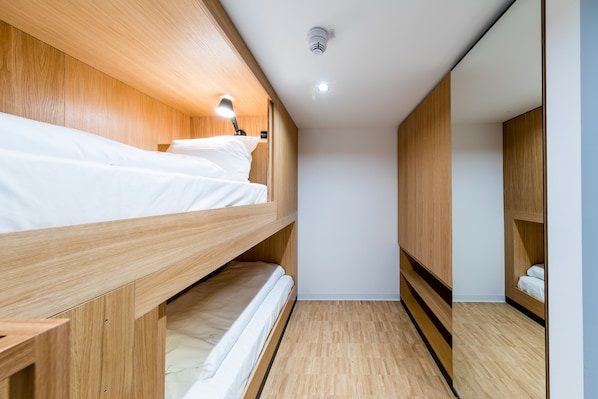 A bunk bed room with wooden walls, a ceiling light, and a small bedside table. - mk | hotel rüsselsheim (Ruesselsheim)