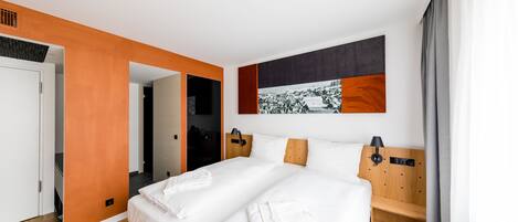 Una habitación de hotel moderna con una cama grande, un cabecero de madera y una obra de arte colgada en la pared.