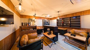 Un espace de détente moderne avec des fauteuils en cuir, une table basse en bois et des luminaires suspendus.
